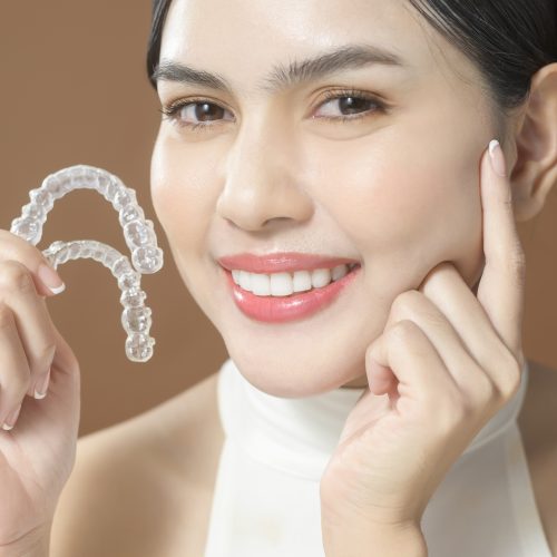 patient-with-beautiful-teeth-holding-invisalign